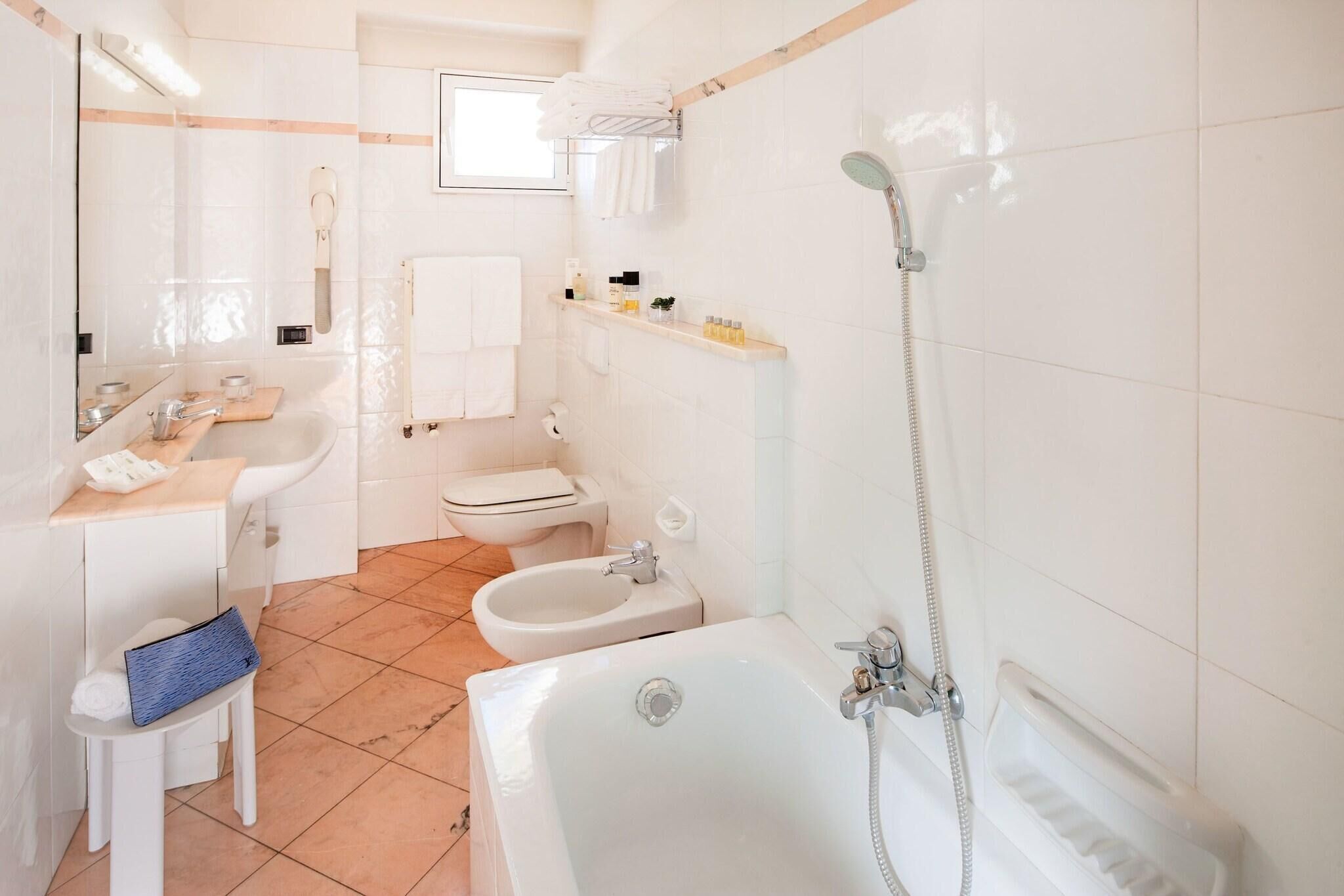 A modern bathroom with a bathtub, shower, bidet, and toilet.