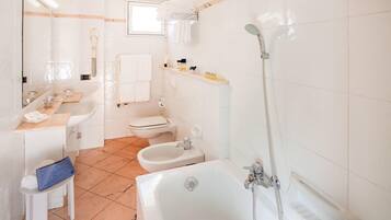 A modern bathroom with a bathtub, shower, bidet, and toilet.
