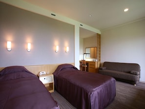 A hotel room with two beds, a desk, a chair, and a sofa. - Furano Hotel (Furano)