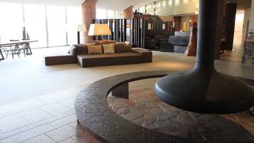 A modern lobby with a stone-tiled floor, a central seating area with sofas and a coffee table, and a large pillar.