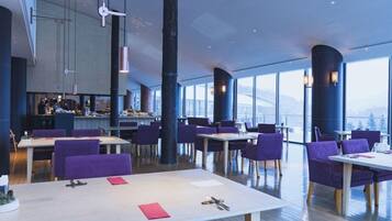 A modern restaurant with high ceilings, large windows, and purple seating.