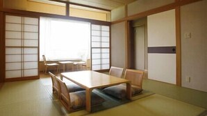 A traditional Japanese room with tatami flooring, a low table, and sliding doors. - Furano Hotel (Furano)