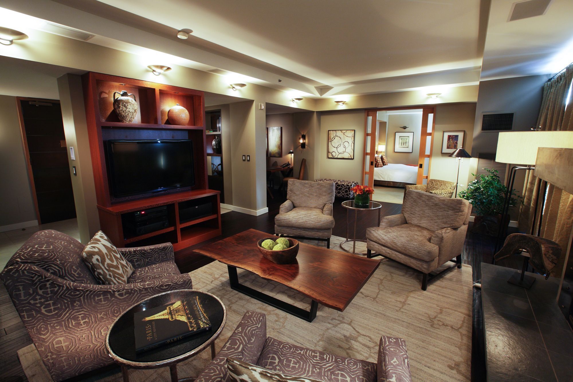 A modern living room with a flat-screen TV, comfortable seating, and a coffee table.