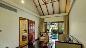 A spacious living area with a wooden ceiling, a pool view, and a dining table with chairs. - Aveda Kumarakom (Kottayam)