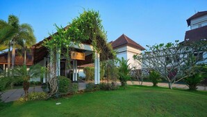 A hotel with a covered entrance, lush greenery, and a clear blue sky. - Aveda Kumarakom (Kottayam)