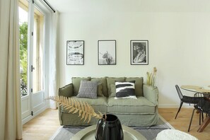 A living room with a sofa, a dining table, and three framed pictures on the wall. - Lovely Apartment Center of Paris (Paris)