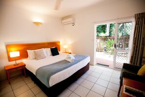 Een hotelkamer met een bed, nachtkastjes, een raam met uitzicht op de omgeving en een airconditioner.