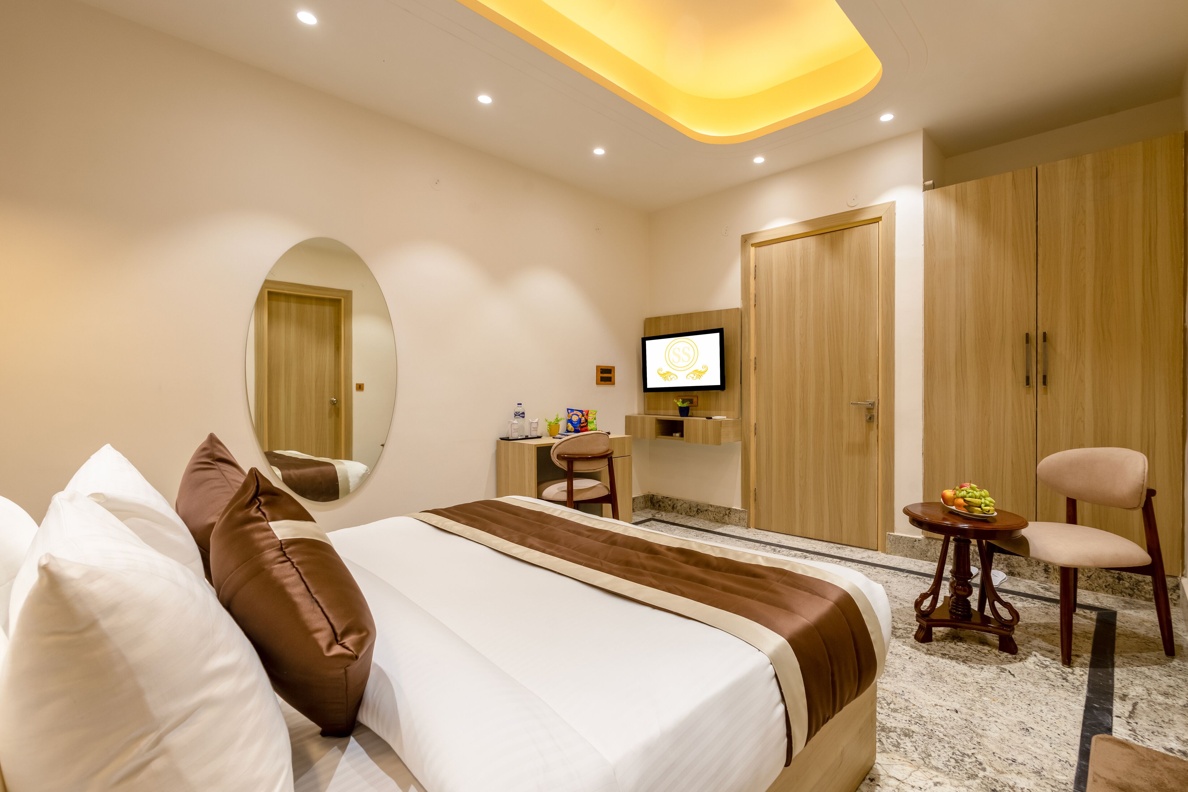 A hotel room with a bed, a desk, a chair, a TV, and a wardrobe.