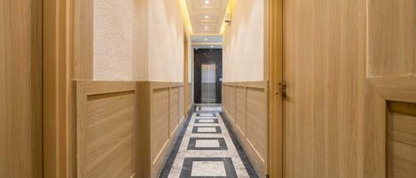 Un pasillo de hotel con paneles de madera, piso estampado y un cartel que indica la habitación 105.