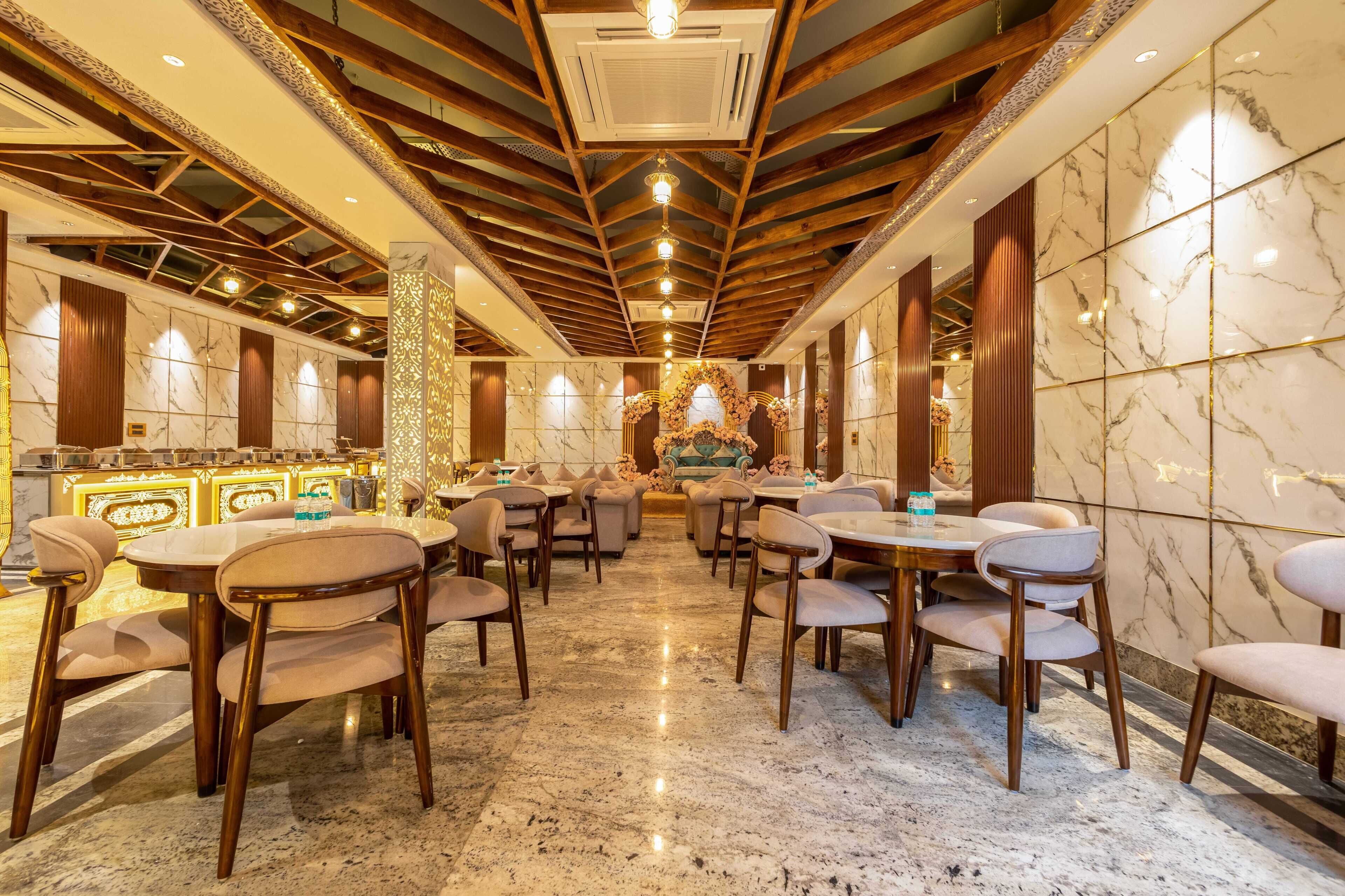 A spacious hotel lobby with marble floors, wooden ceiling beams, and a central floral arrangement.