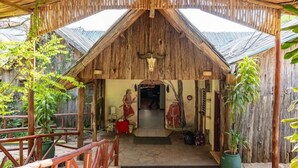 A rustic wooden structure with a thatched roof, a bull skull decoration, and a mural of two figures. - Sentrim Mara Lodge (Maasai Mara)