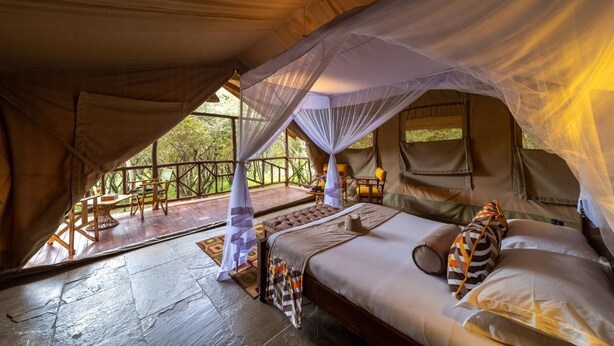 A tented accommodation with a bed, a small table, and chairs. - Sentrim Mara Lodge (Maasai Mara)