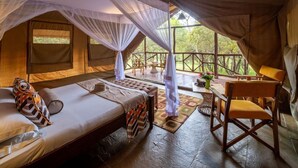 A tented room with a bed, a chair, and a table with a view of the outdoors. - Sentrim Mara Lodge (Maasai Mara)