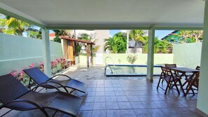 Eine überdachte Terrasse mit Pool, Liegestühlen und Tisch.