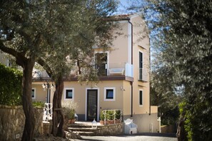 A two-story building with a balcony, a stone wall, and potted plants. - Melrose Relais (Massa Lubrense)