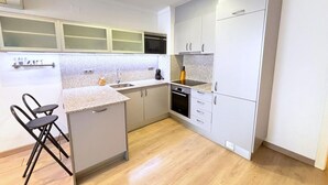 Cocina compacta con microondas, lavamanos y una pequeña isla con asientos.