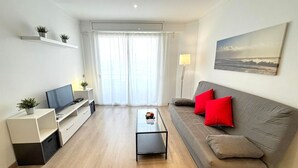 Una sala de estar moderna con un sofá, una mesa de centro, un televisor y plantas.