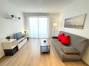 A modern living room with a sofa, coffee table, TV, and plants. - Renovated beachfront apartment in Roses, air conditioning and elevator (Roses)