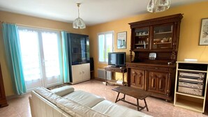 Un salon comprenant un canapé, un téléviseur, un meuble et une petite table.