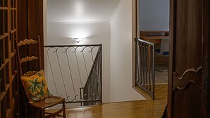 A wooden staircase with a metal railing, a wooden door, and a chair with a cushion. - Spacious Lodge in Nargis with Private Parking, Near Paris (Nargis)