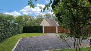 A residential property with a gravel driveway, a wooden fence, and a well-maintained lawn. - Spacious Lodge in Nargis with Private Parking, Near Paris (Nargis)