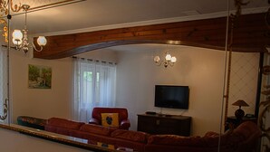 A living room with a large mirror, a red sofa, a television, and a wooden ceiling. - Spacious Lodge in Nargis with Private Parking, Near Paris (Nargis)