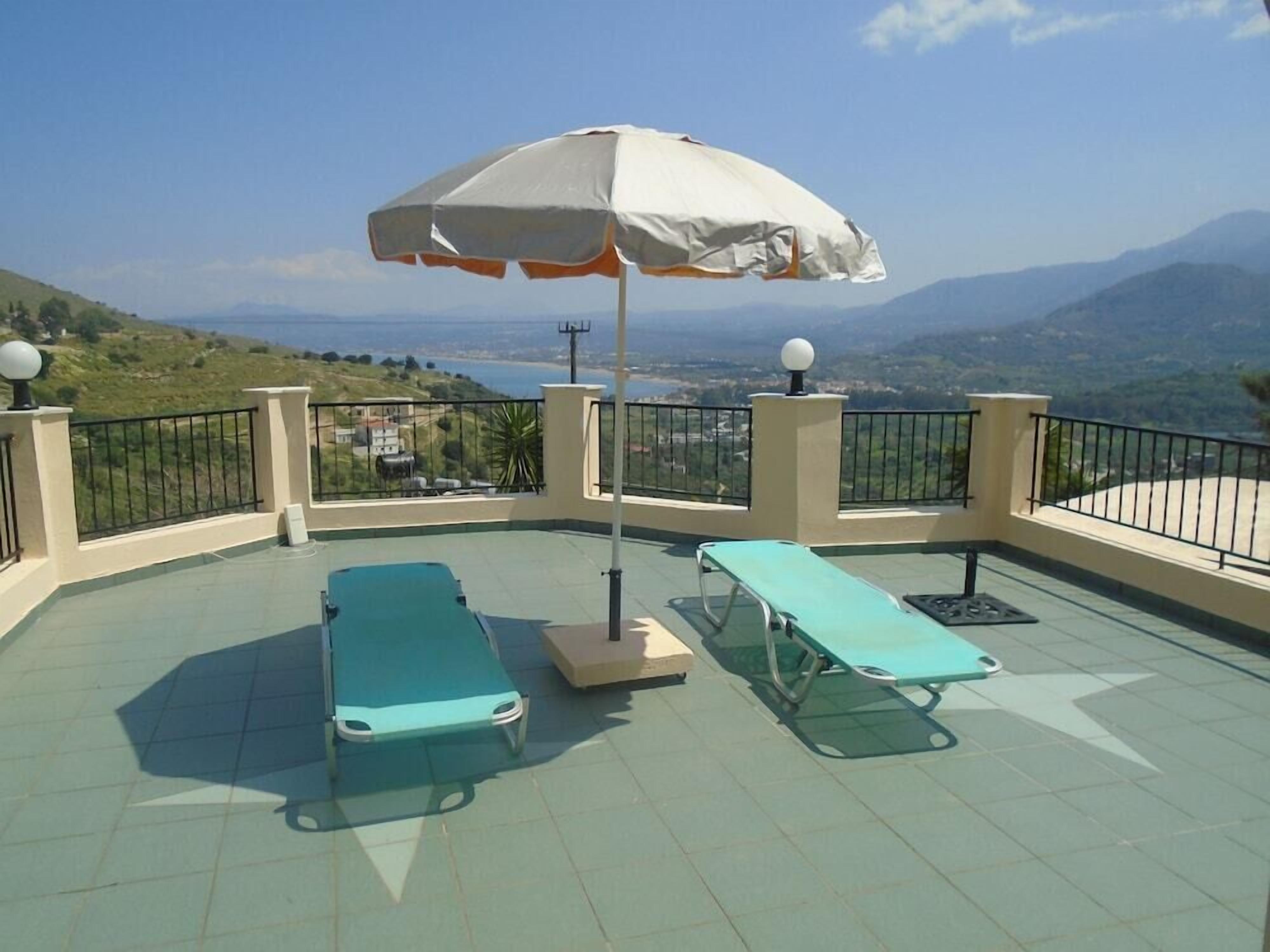 Una terrazza sul tetto con due poltrone e un ombrellone grande, con vista su un paesaggio suggestivo.