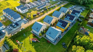 Zona residencial amb diverses cases, algunes amb panells solars, i un parc infantil.