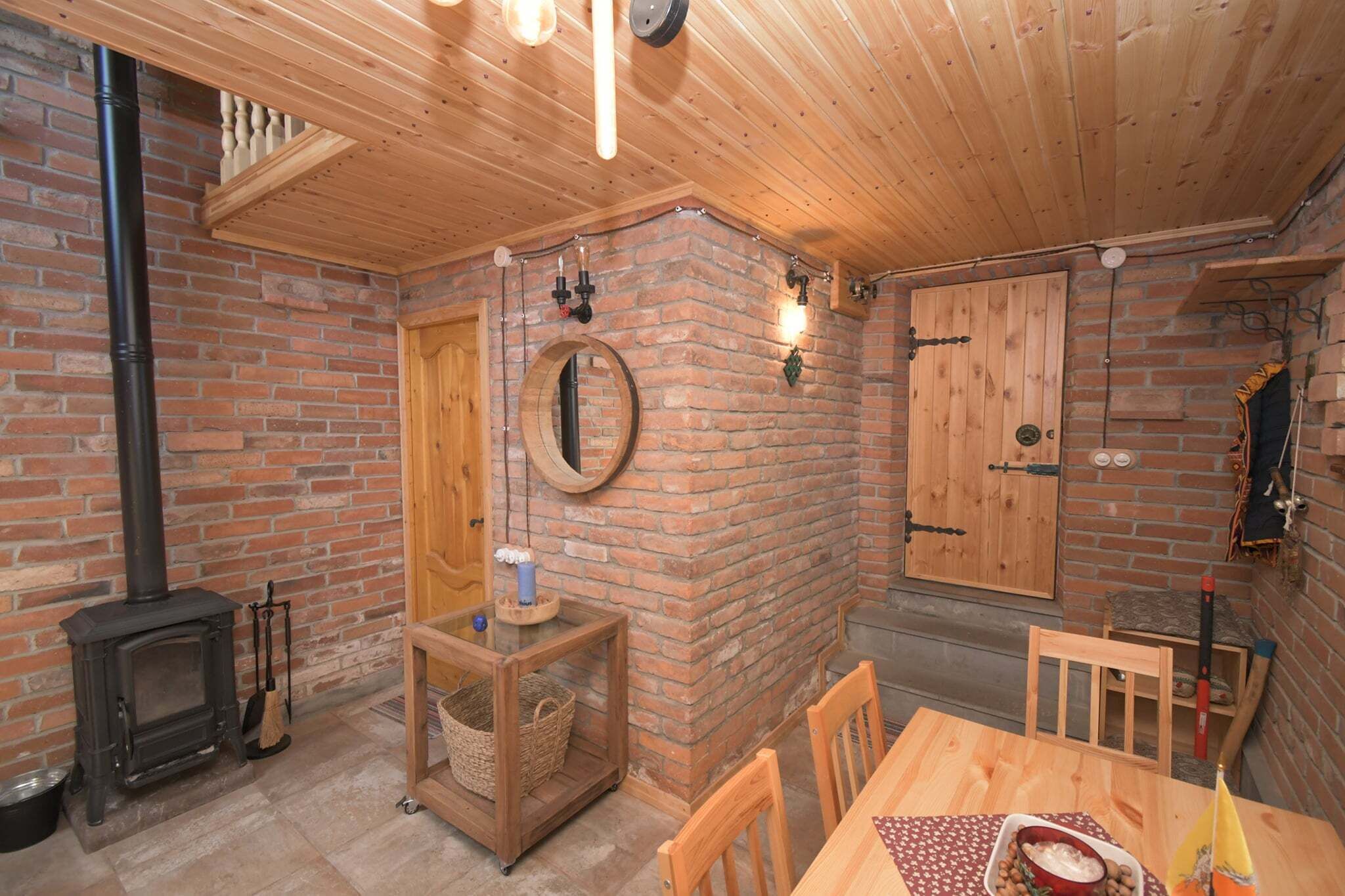Una habitación acogedora con chimenea de ladrillo, techo de madera y una mesa de comedor con sillas.