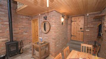 Una habitación acogedora con chimenea de ladrillo, techo de madera y una mesa de comedor con sillas.