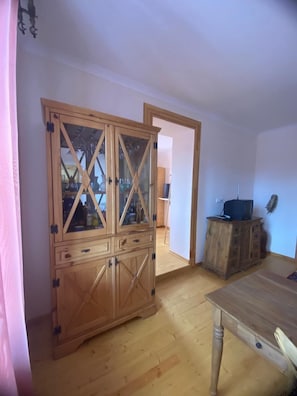 Une pièce comprenant un meuble en bois, un téléviseur posé sur un meuble en bois, et une table à manger.