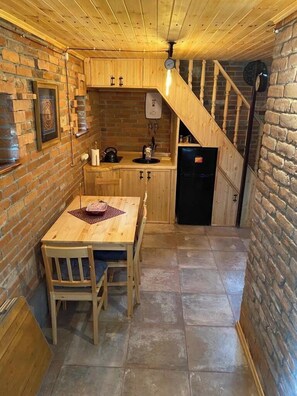 Une cuisine chaleureuse avec des meubles de rangement en bois, un réfrigérateur noir et une table à manger avec des chaises.