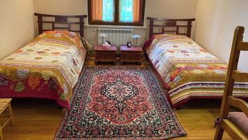 Un dormitorio con dos camas individuales, un tapete grande con diseño, muebles de madera y una ventana con cortinas.