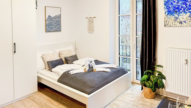 A modern bedroom with a bed, pillows, a blanket, and a plant. - Luna Apartment Passau - Balcony - Kitchen - Self Checkin - Parking lot (Passau)