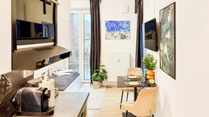 A modern living room with a sofa, a coffee table, a TV, and a dining area with a table and chairs. - Luna Apartment Passau - Balcony - Kitchen - Self Checkin - Parking lot (Passau)