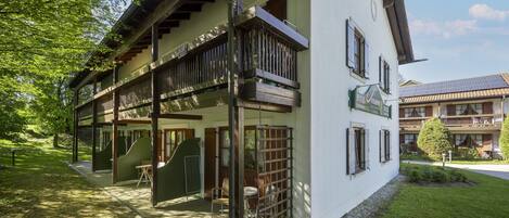 A hotel with a balcony, a covered outdoor seating area, and a sign indicating it is a hotel.