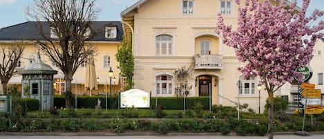 En bygning med et skilt, der viser 'Fruchtwirtshaus', og en blomsterhave foran.