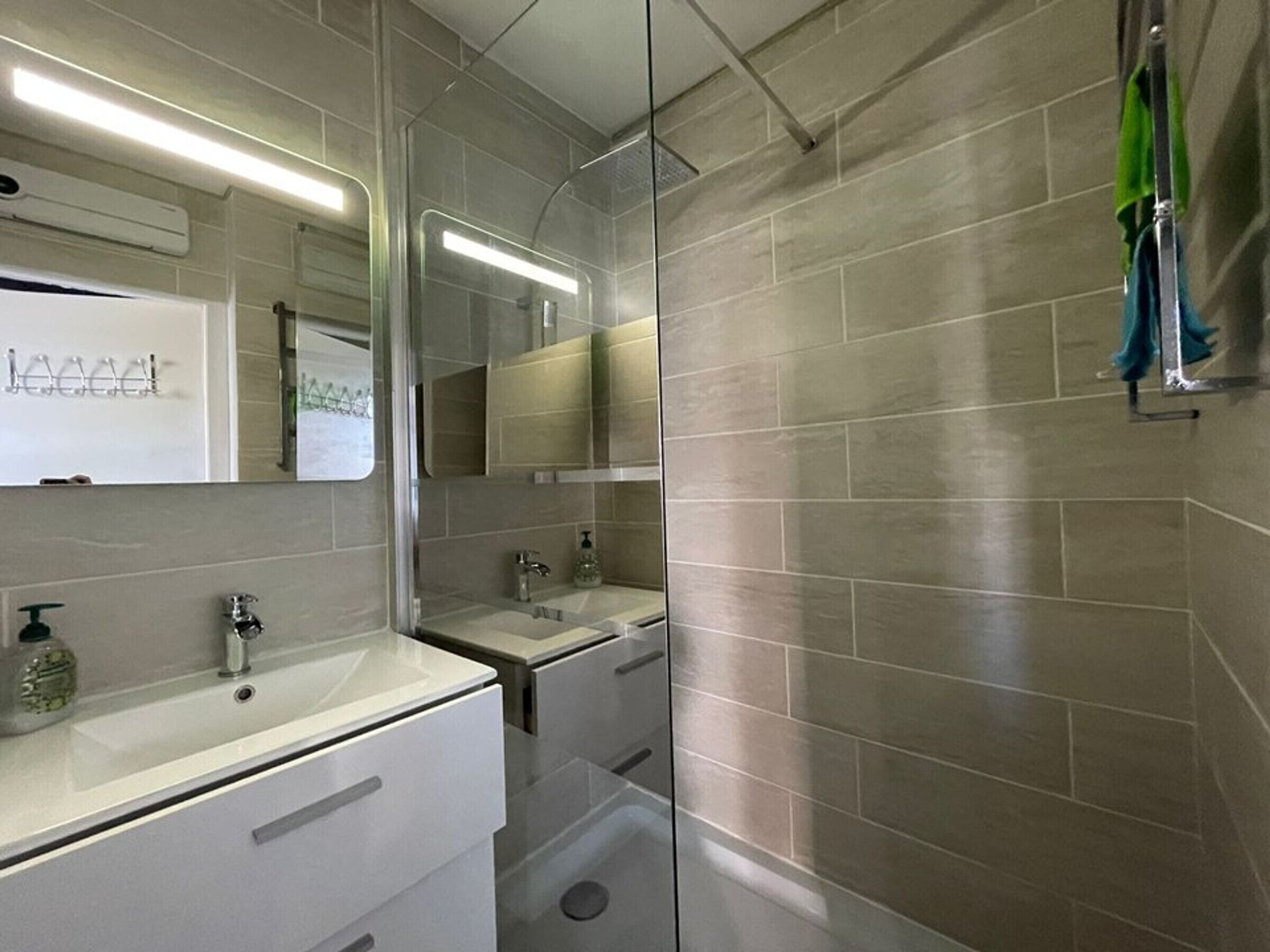 Une salle de bain moderne avec deux lavabos, une douche à l’italienne et un miroir.