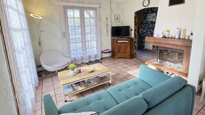 Uma sala de estar com sofá, televisão, lareira e janela com cortinas.