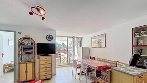 Een eethoek met een tafel, stoelen, een televisie en een kast.