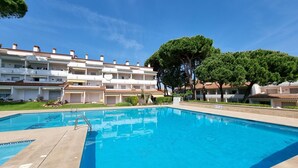 A swimming pool with a clear blue water surface, surrounded by a multi-story building with balconies and a well-maintained lawn. - Apartment 400m from the beach with communal pool (L'Escala)