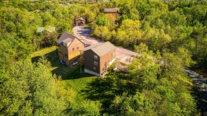 A large, multi-story building surrounded by dense greenery, with a clear view of the surrounding landscape. - Royal Bliss - Mountain Views Theater Hot Tub (Sevierville)