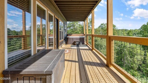 A wooden deck with a covered area, large windows, and a view of the surrounding greenery. - Royal Bliss - Mountain Views Theater Hot Tub (Sevierville)