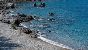 Una costa rocosa con aguas azul cristalino y rocas dispersas.
