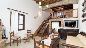 Una sala de estar acogedora con chimenea, muebles de madera, una escalera y un televisor.