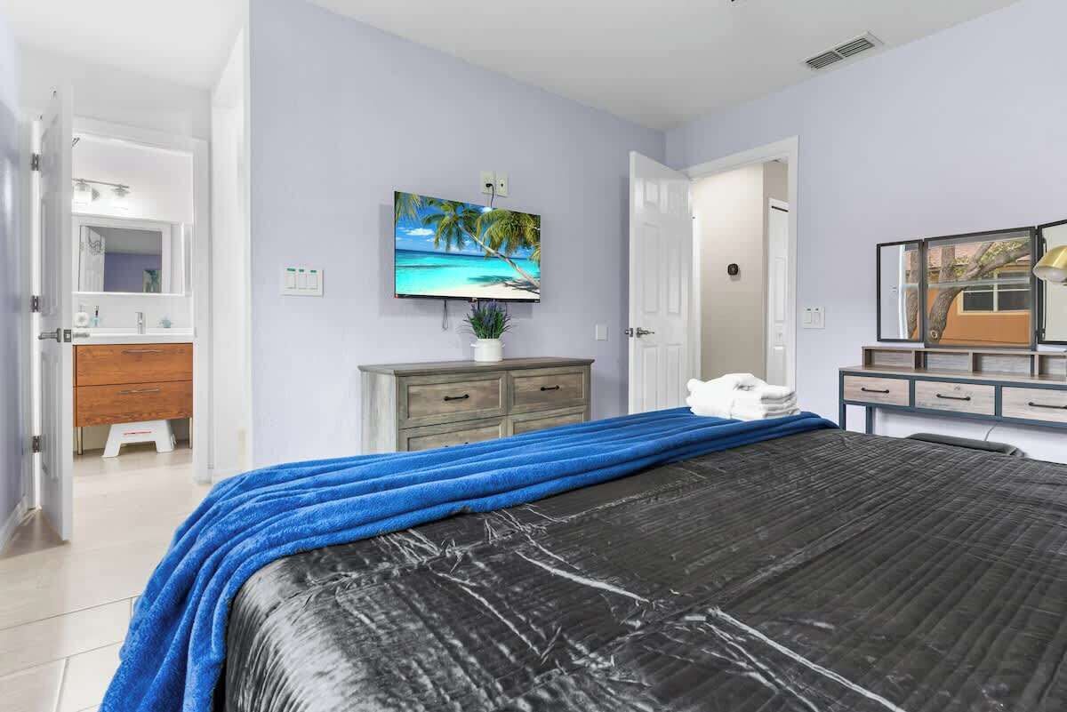 Un dormitorio con una cama, un televisor montado en la pared, un aparador y un espejo.