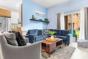 Un salon moderne avec un mur bleu, un canapé gris, une table basse en bois et une petite plante.