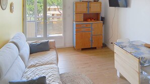 Une pièce comprenant un canapé, une armoire, un téléviseur et un ventilateur de plafond.