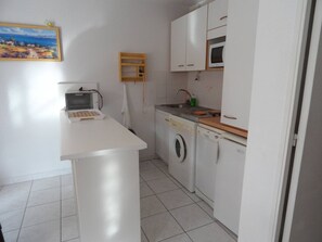 Eine kleine Küche mit Mikrowelle, Waschmaschine und Spüle.