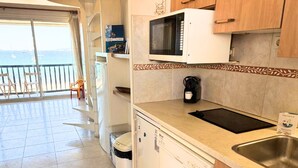 Une cuisine avec vue sur la mer, un four à micro-ondes, une machine à café et un lave-vaisselle.